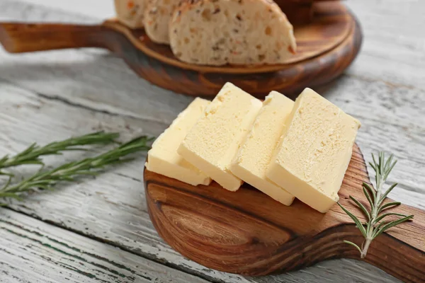 用新鲜黄油和美味的面包铺在木制桌子上的切菜板 — 图库照片