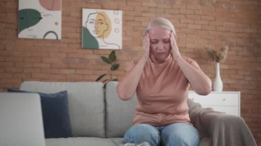 Stresli olgun kadın evdeki kanepede oturuyor.