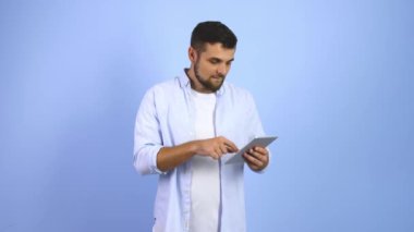 Tablet bilgisayarlı mutlu genç adam başarısını renk geçmişiyle kutluyor.