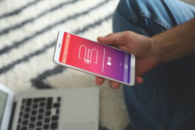 Evdeki modern akıllı telefonlarda sesli kitap uygulaması kullanan bir adam.