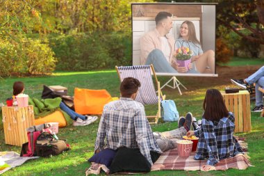 Arkadaşlar açık hava sinemasında film izliyor.