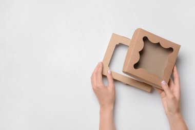 Beyaz arkaplanda karton kutular olan eller