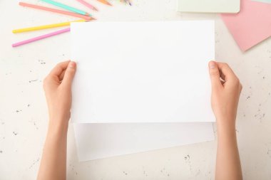 Işık arkaplanı üzerinde boş kağıdı olan kadın eller