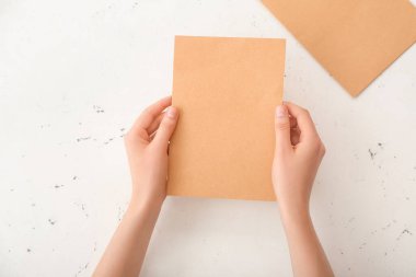 Işık arkaplanı üzerinde boş kağıdı olan kadın eller