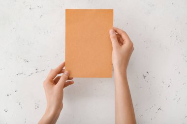 Işık arkaplanı üzerinde boş kağıdı olan kadın eller