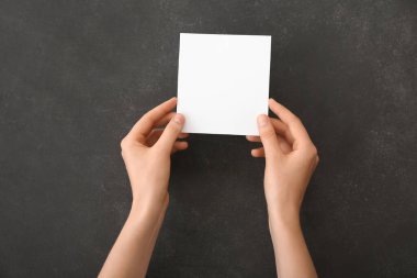 Koyu arkaplanda boş kağıda sahip kadın elleri