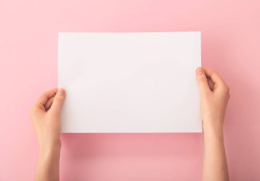 Renk arkaplanı üzerinde boş kağıdı olan kadın elleri
