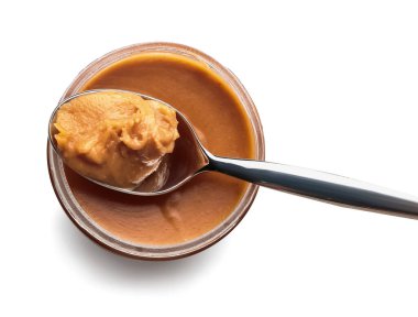 Fıstık ezmesi ve kaşık kavanozu beyaz arka planda izole edilmiş.