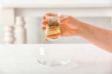 Bir bardak yeşil çayla kadın eli, yakın plan.