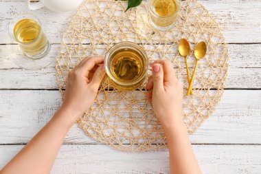 Ahşap masada yeşil çay fincanı olan kadın elleri