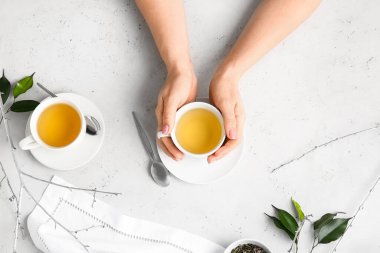 Masada bir fincan yeşil çay ile kadın elleri.