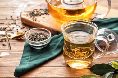 Ahşap masada yeşil çay eşliğinde kompozisyon.