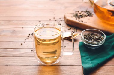 Ahşap masada yeşil çay eşliğinde kompozisyon.