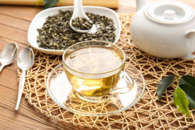 Ahşap masada yeşil çay eşliğinde kompozisyon.