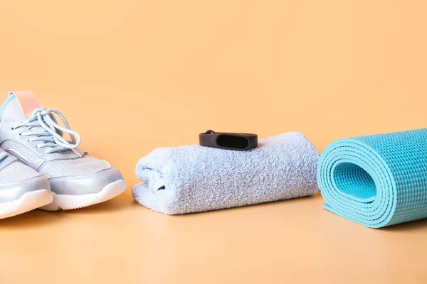Sportive shoes, towel and yoga mat on light background