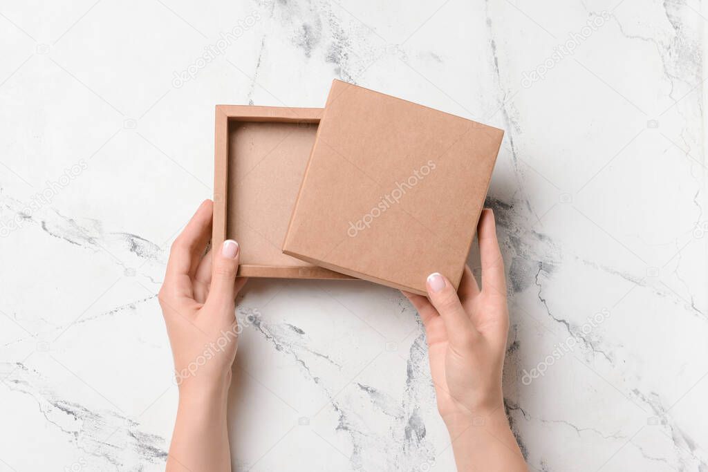 Hands with cardboard box on light background