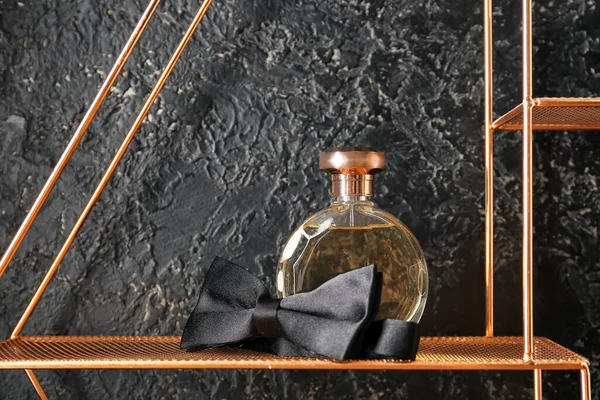 stock image Bottle of perfume and bowtie on dark background