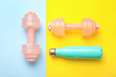 Renkli arka planda şık halterler ve bir şişe su