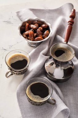 Cezve, bir fincan kahve ve masada hurma.