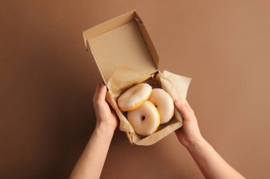 Renkli arka planda lezzetli çöreklerle dolu bir kadın eli.