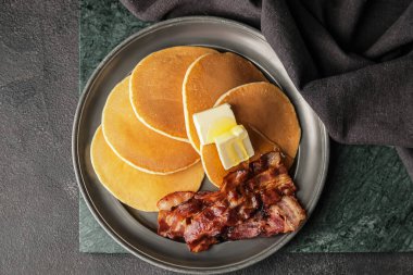 Koyu arkaplanda kızarmış domuz pastırması ve tereyağlı lezzetli krepler.