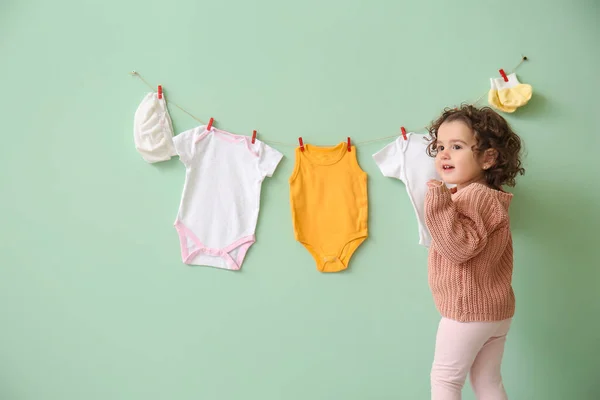 可爱的女婴 靠近挂在彩墙上的时髦衣服 — 图库照片