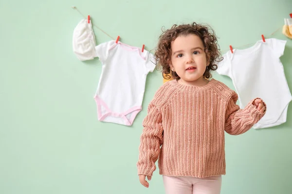 可爱的女婴 靠近挂在彩墙上的时髦衣服 — 图库照片