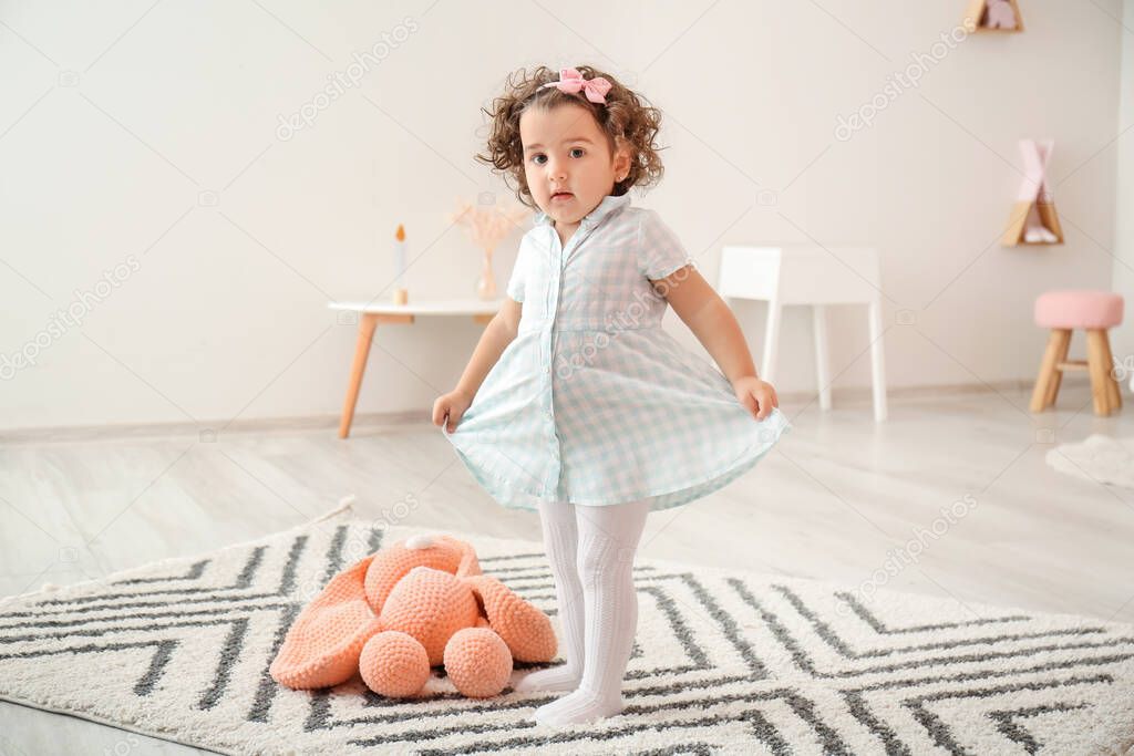 Cute baby girl in stylish dress at home