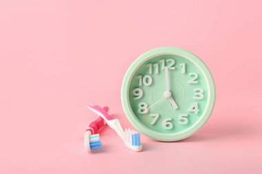 Renkli arkaplanda çalar saat ve diş fırçaları