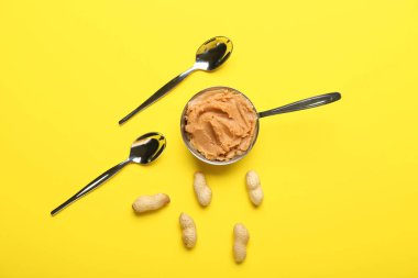 Lezzetli fıstık ezmeli, fındıklı ve kaşık renkli arka planda