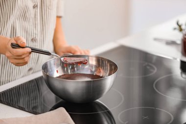 Kadın mutfakta ahududu reçeli pişiriyor.