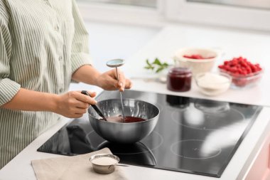 Kadın mutfakta ahududu reçeli pişiriyor.