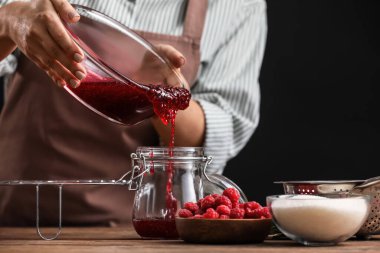 Kadın mutfakta ahududu reçeli pişiriyor.