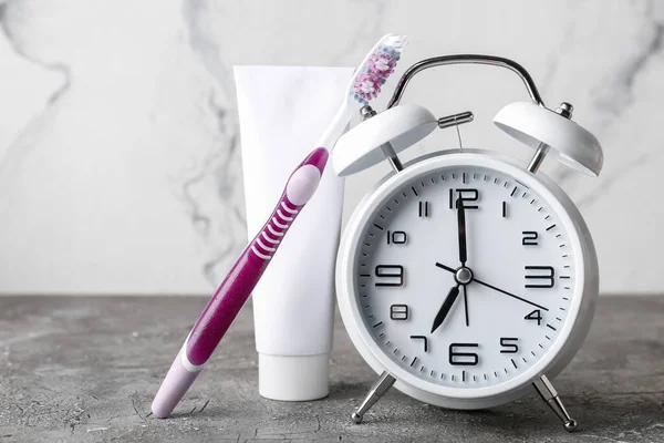 目覚まし時計テーブルの上のペーストと歯ブラシ — ストック写真
