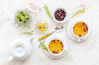 Bitkiler, çaydanlık ve fincanlar hafif arka planda çiçekli çay.