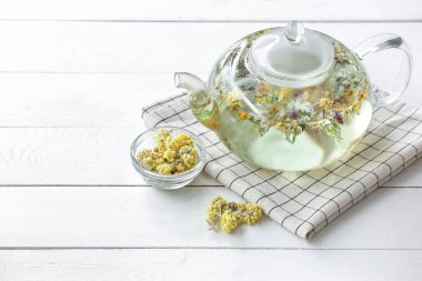 Çiçekli çaydanlık ve arka planda kuru çiçekler.