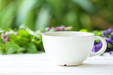 Arka planda bulanık duran çiçekli çay bardağı.