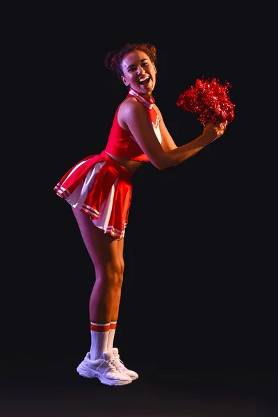 Beautiful young cheerleader on dark background