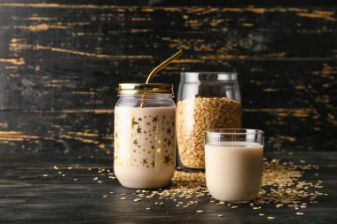 Meyve suyu kavanozu ve ahşap arka planda yulaf sütüyle birlikte bardak.