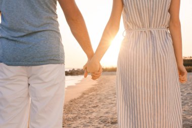 Deniz kıyısında el ele tutuşan mutlu genç çift