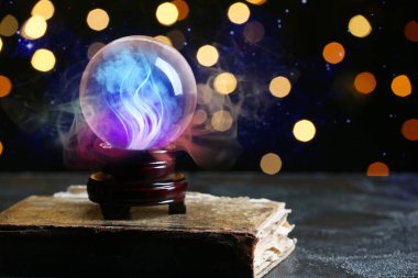 Yazım kitabı ve kristal falcı küresi masada.