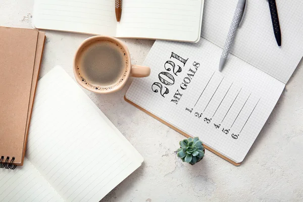 2021 için yapılacaklar listesi olan defter, beyaz arkaplanda bir fincan kahve ve kırtasiye.