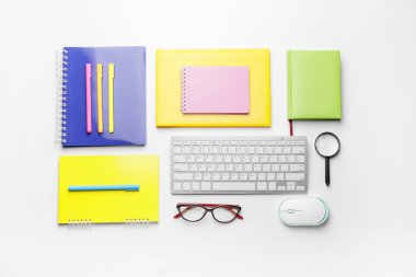 Composition with computer keyboard, mouse, magnifying glass and stationery on white background