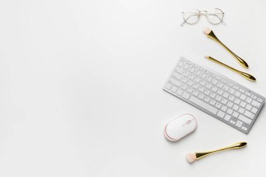 Composition with computer keyboard, mouse and makeup brushes on white background