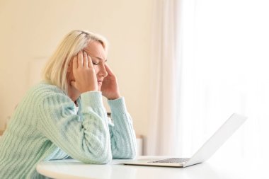 Evde baş ağrısı çeken stresli olgun bir kadın.