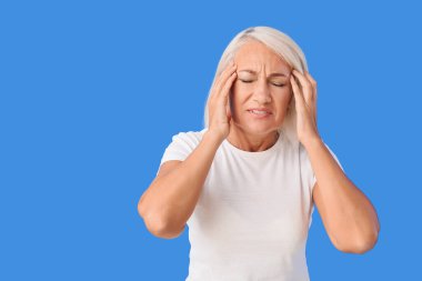 Arka planda baş ağrısı çeken stresli olgun bir kadın.