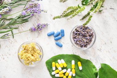 Bitki bazlı haplar ve kase, arka planda kuru çiçekler.