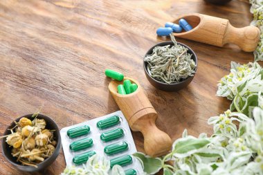 Bitki bazlı haplar ve ahşap arka planda kuru otlar.