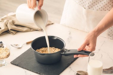 Kadın mutfakta lezzetli yulaf ezmesi pişiriyor.