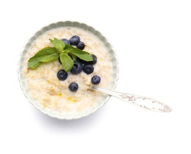 Beyaz arka planda lezzetli yulaf ezmesi ve yaban mersinli kase